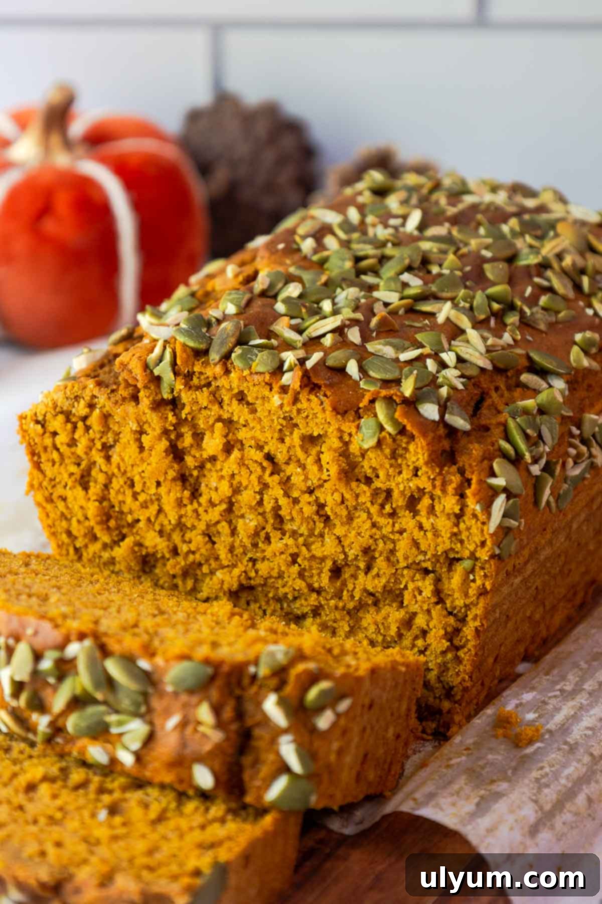 Pumpkin Spice Cake Loaf 2 A close-up of sliced pumpkin bread topped with pepitas, revealing its moist crumb.
