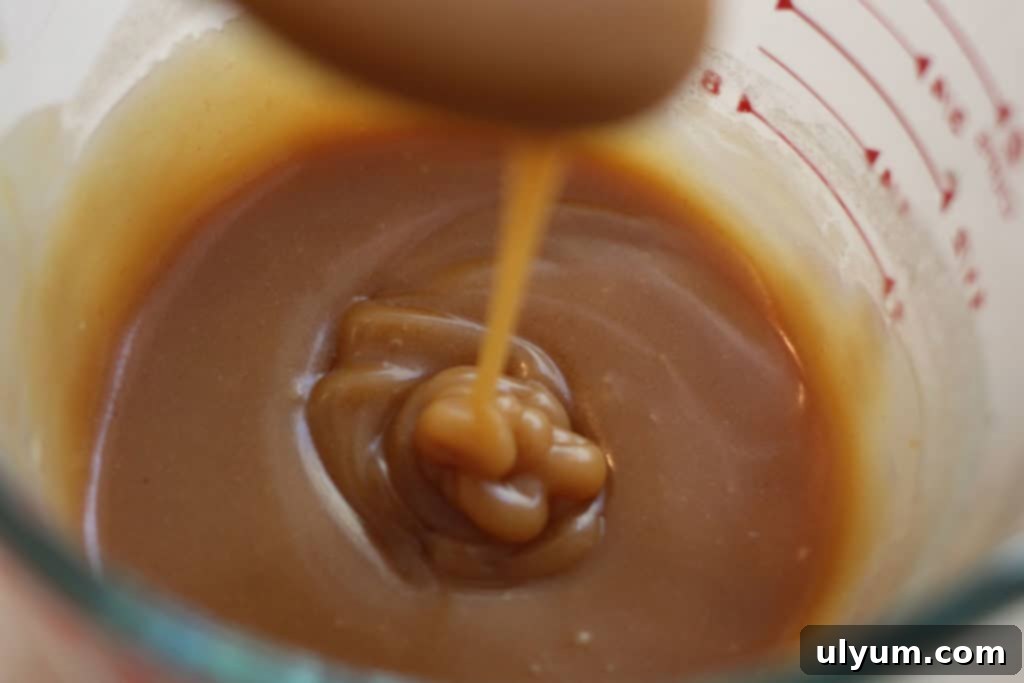Thick peanut butter pancake syrup dripping enticingly off of a spoon.