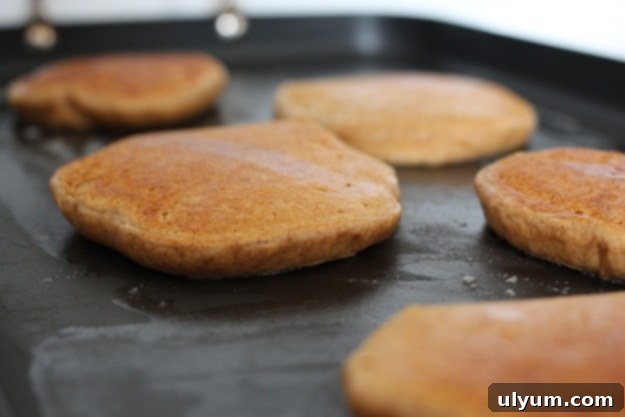 Pancakes cooking on the griddle, golden brown and bubbling.