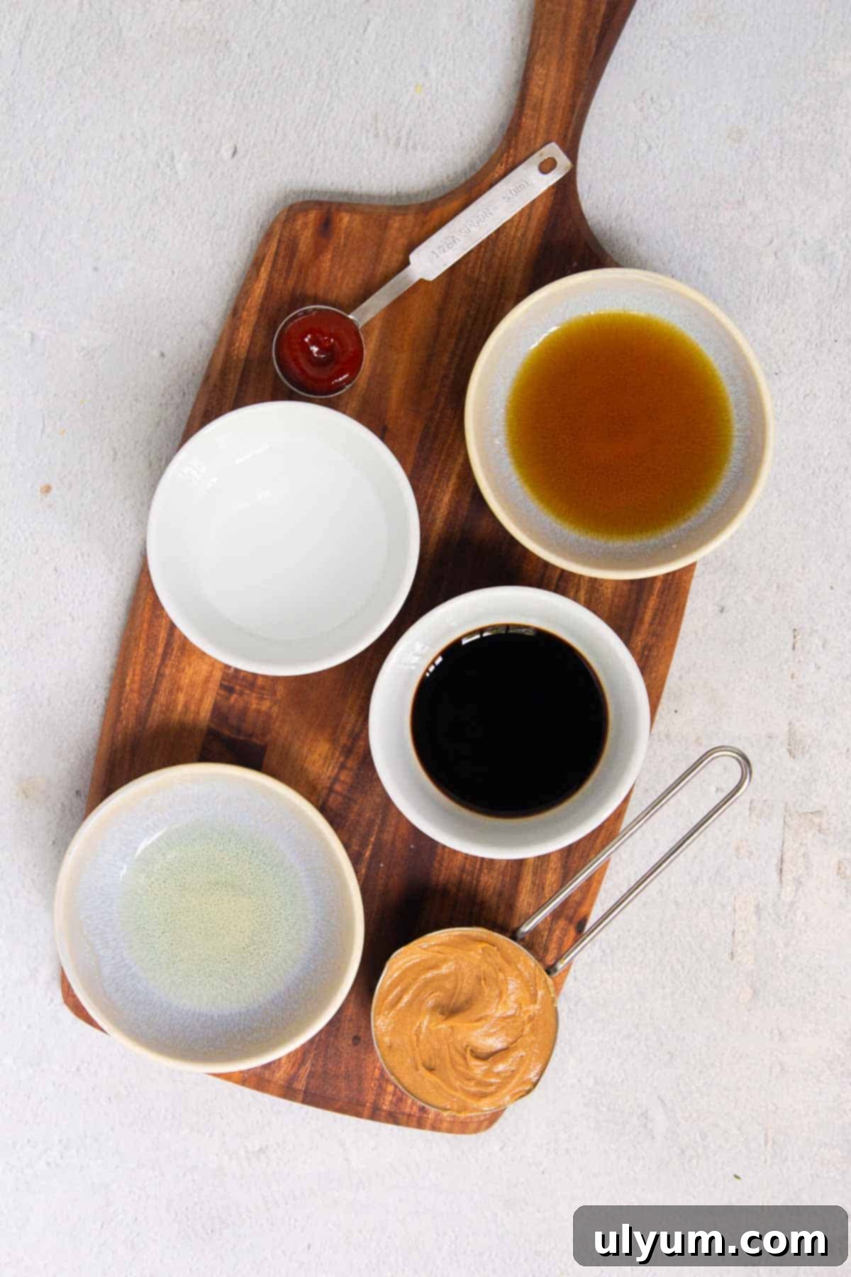 Effortless Five Ingredient Peanut Sauce 3 A visual display of the five simple ingredients needed to make peanut sauce: creamy peanut butter, soy sauce, maple syrup, rice vinegar, and sriracha.