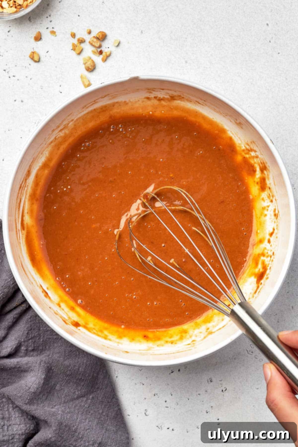 Effortless Five Ingredient Peanut Sauce 5 The peanut sauce ingredients are shown whisked together in a medium mixing bowl, now smooth and creamy, ready for serving.