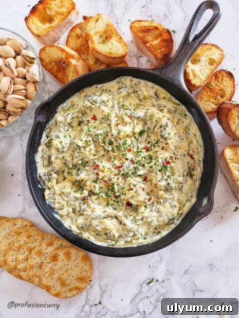 Score Big: 48 Instant Pot & Slow Cooker Game Day Eats 12 Instant Pot Spinach Artichoke Dip, served in a cast iron skillet.