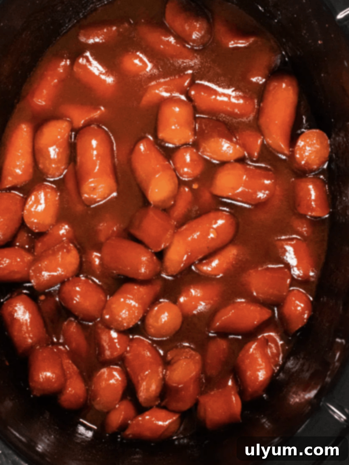 Score Big: 48 Instant Pot & Slow Cooker Game Day Eats 19 Hot dogs cut in small bite size pieces covered in BBQ sauce in a slow cooker.