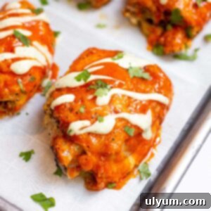 Close up of buffalo chicken thigh topped with avocado lime ranch and fresh parsley.