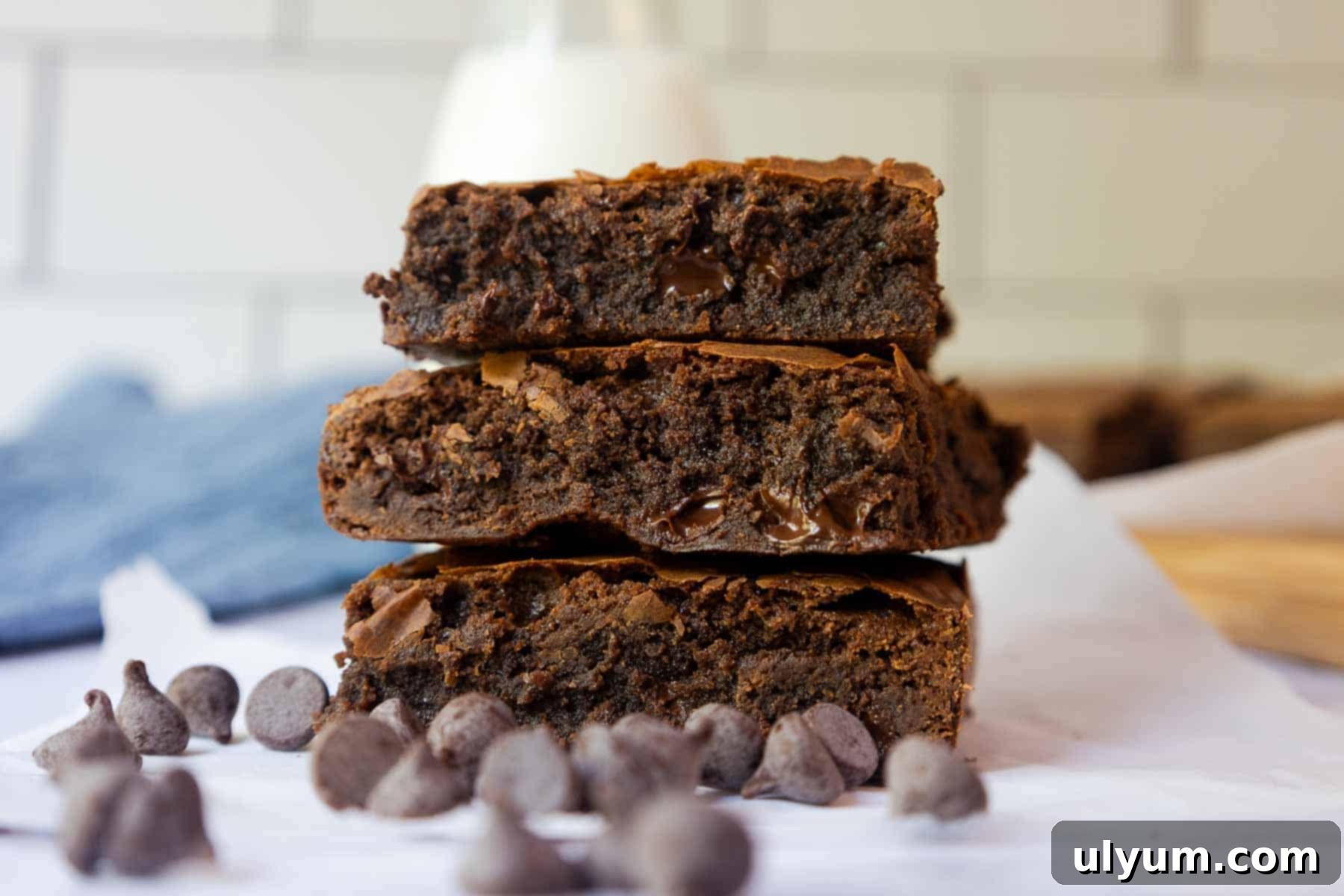 Stack of three thick, fudgy brownies with visible melted chocolate chips.