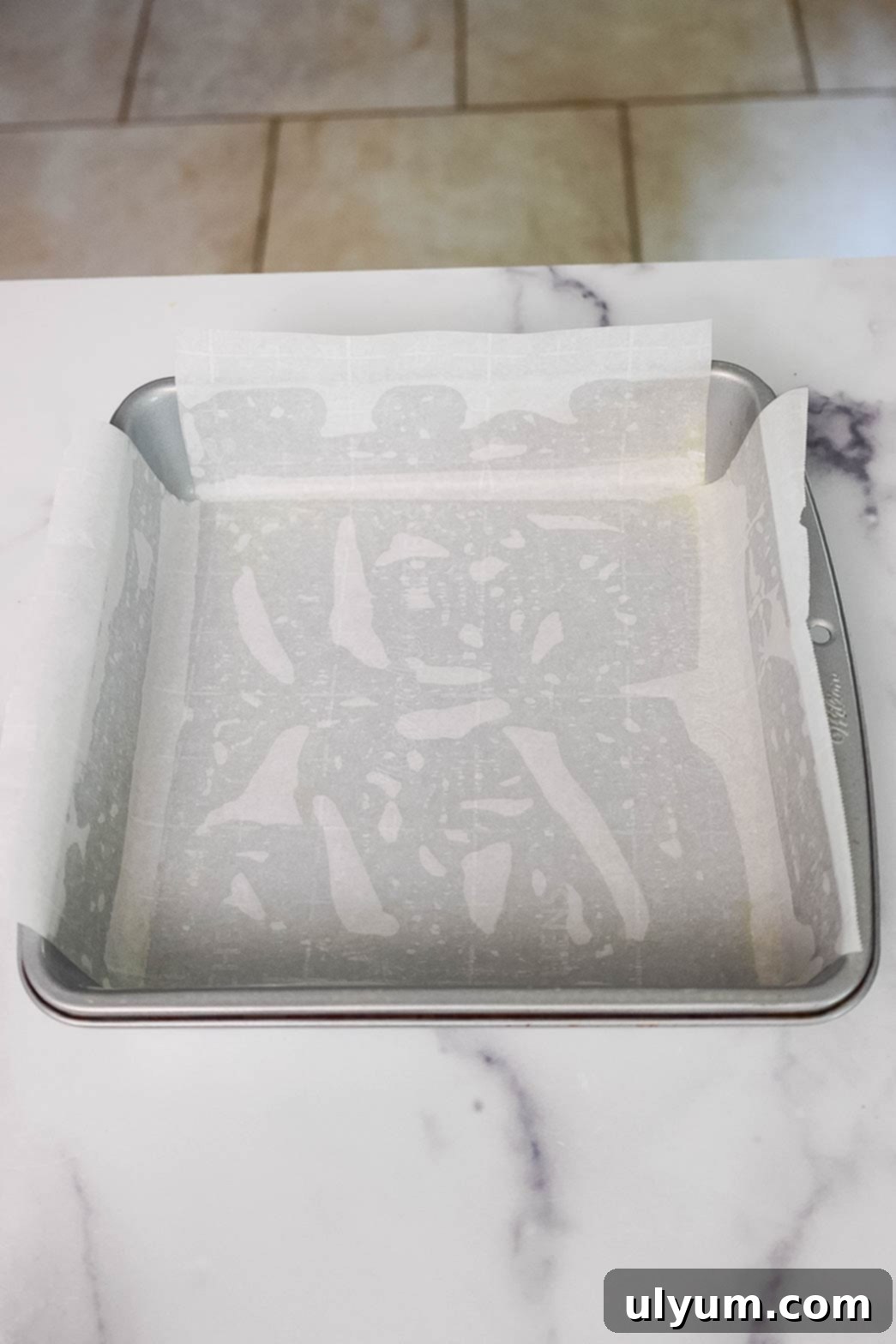 Square metal baking pan lined with parchment paper.