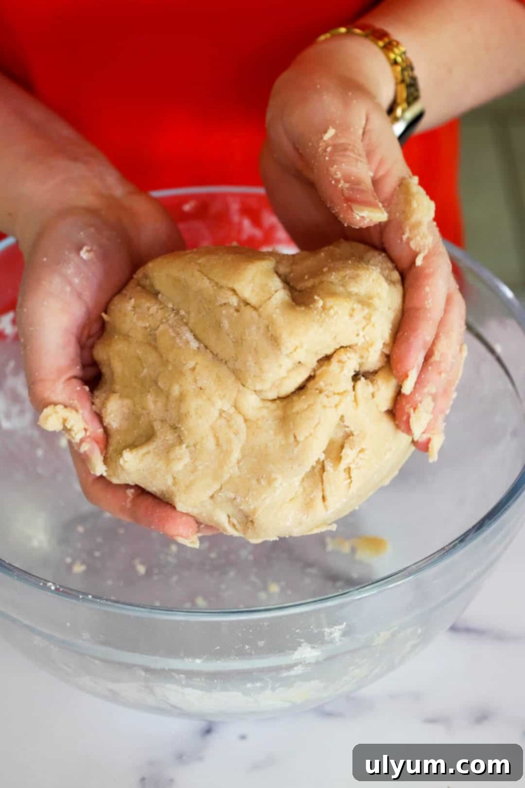 Hands forming the finished dough until it comes together in one cohesive ball.