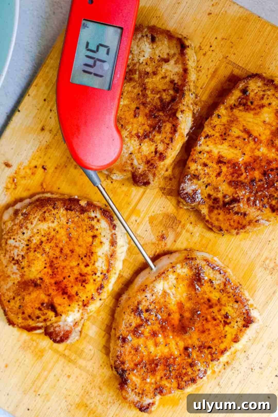 Cooked pork chops on a board with a meat thermometer reading 145°F.