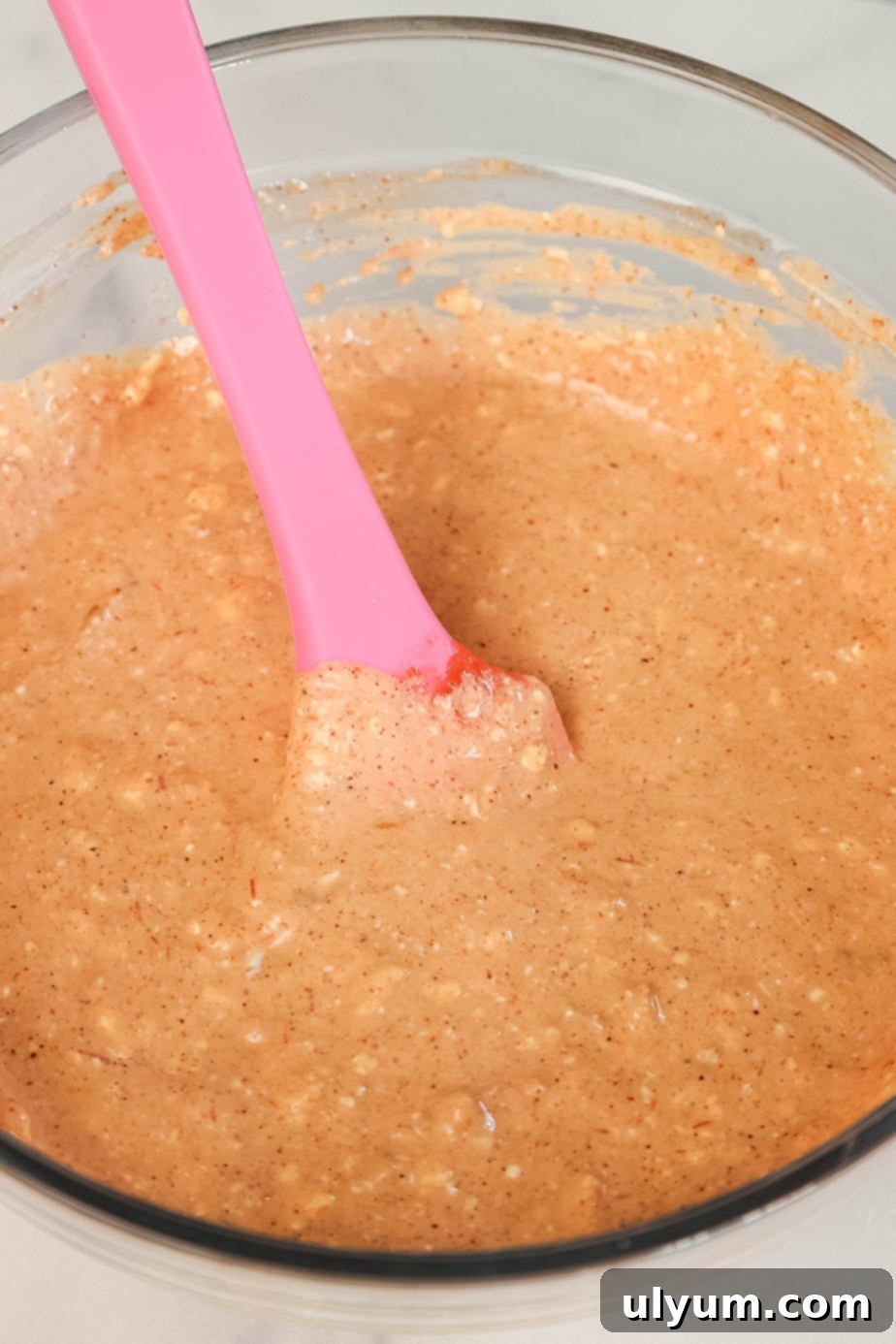 Cream cheese, salsa, and taco seasoning being combined in a bowl with a spatula.