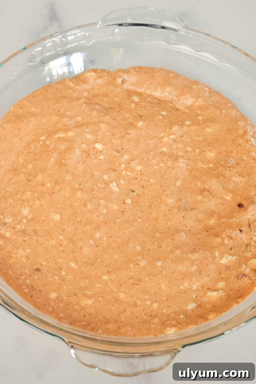 The cream cheese and salsa base spread evenly in a pie dish before toppings are added.